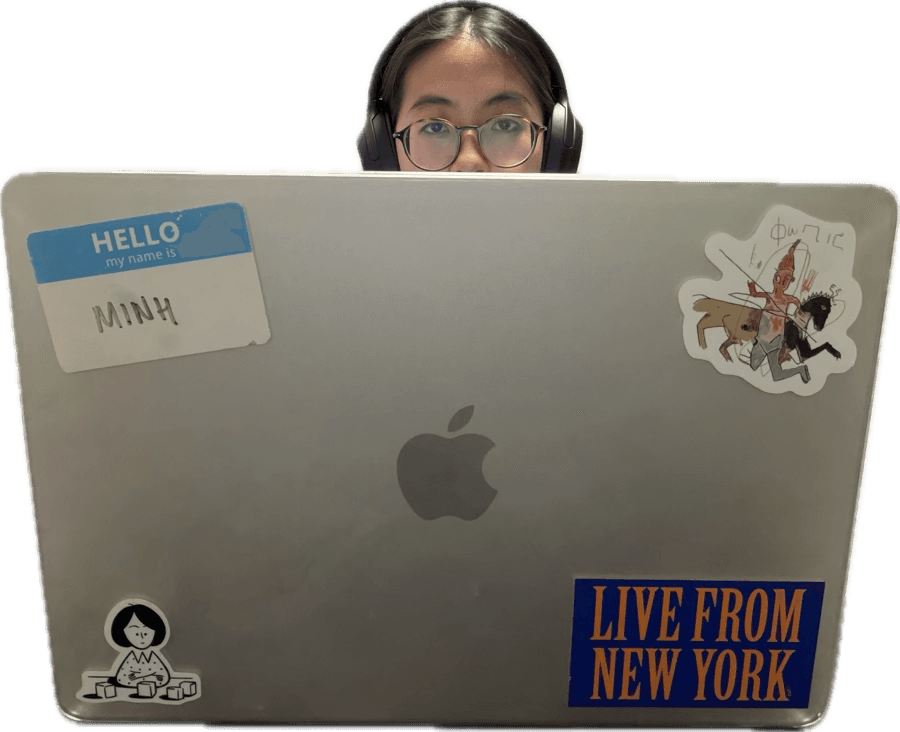 Minh Nguyen peeking over a laptop covered in stickers